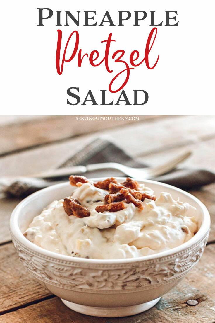 Pineapple pretzel salad in a pretty white bowl with a gray cloth napkin and silver fork on a wooden pallet board.