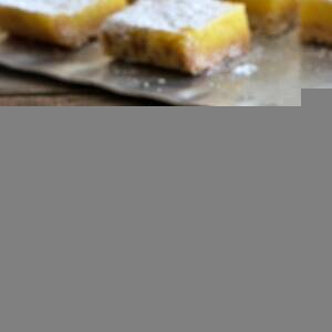 Whole lemon bars dusted with powdered sugar, cut into squares and served on a silver platter