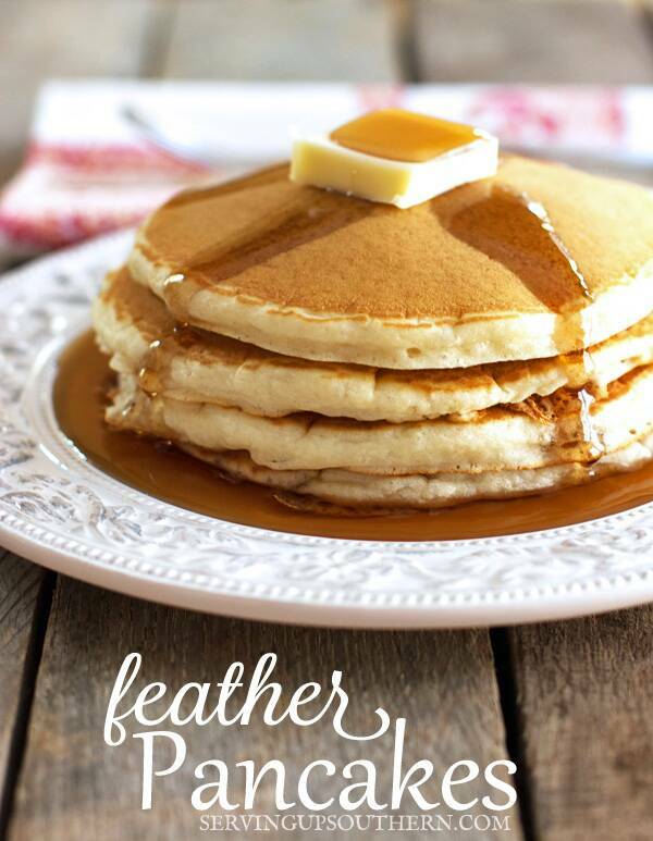 A stack of homemade pancakes tops with a pat of butter and syrup on a pretty white plate.