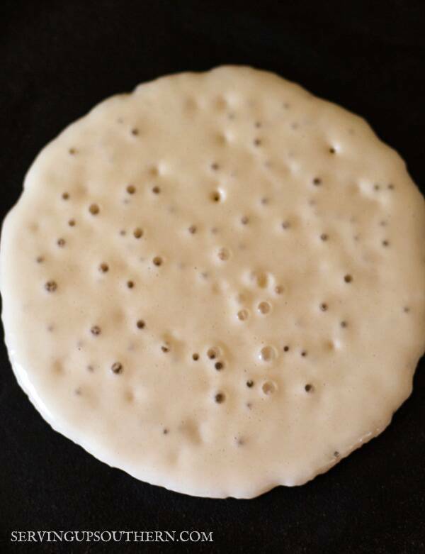 A bubbly pancake cooking in a cast iron pan.