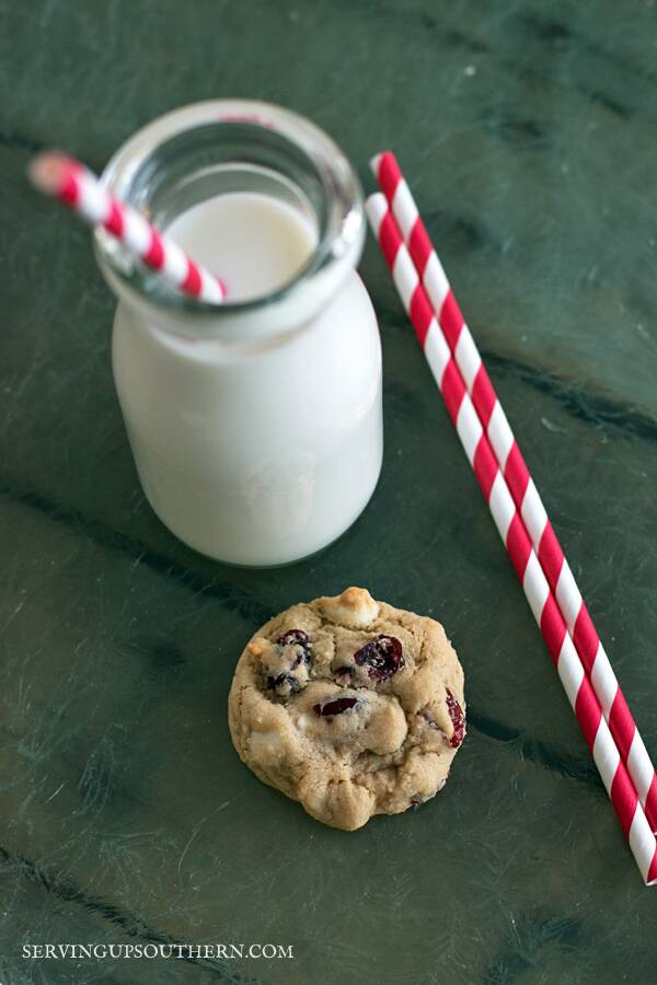 White Chocolate Cranberry Cookies and a glass of milk on a tray.