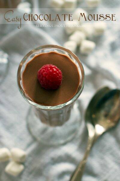 Four elegant glass pudding cups filled with chocolate mousse and topped with a raspberry.