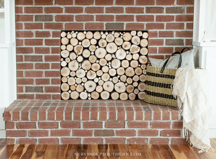 How to make a stacked log fireplace screen / A straw bag, pillow, and throw sitting on a hearth.