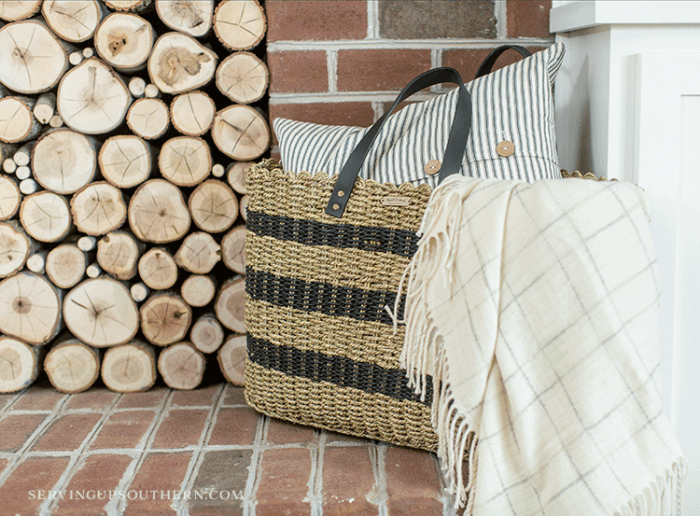 How to make a stacked log fireplace screen / A straw bag, pillow, and throw sitting on a hearth.