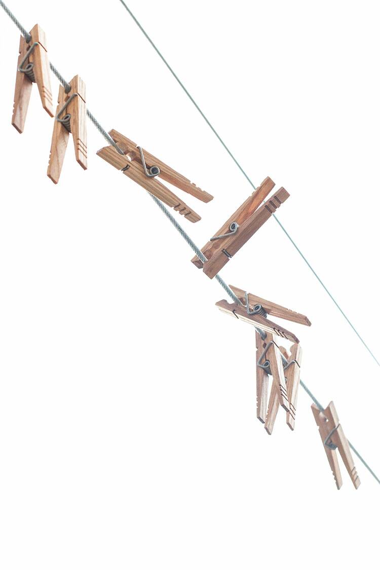 Twelve clothespins pinned on a line with the sky in the background.