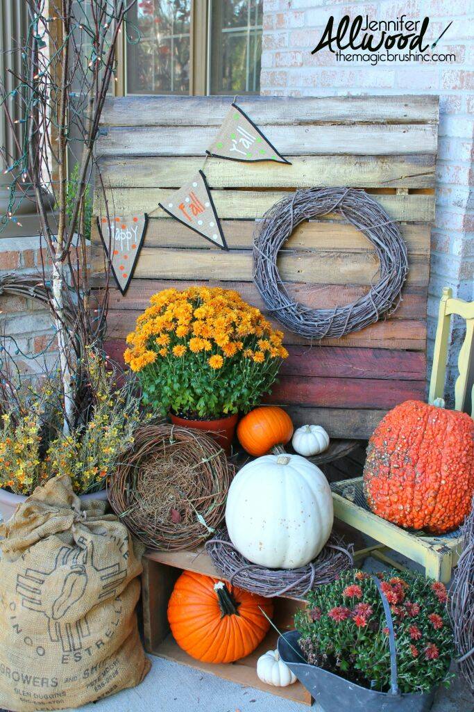Wooden pallet painted in fall colors propped on porch with pumpkins.