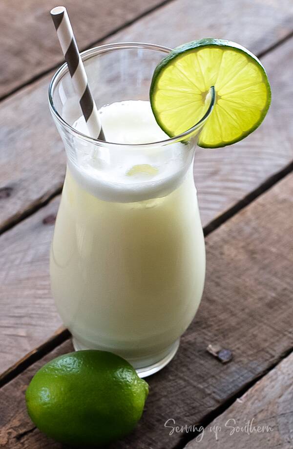 A glass of frothy Brazilian lemonade on a wooden board