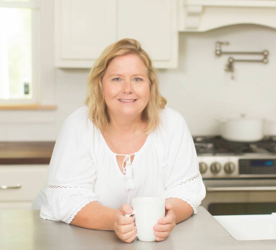 Picture of Kim standing at her kitchen island with cup of coffee