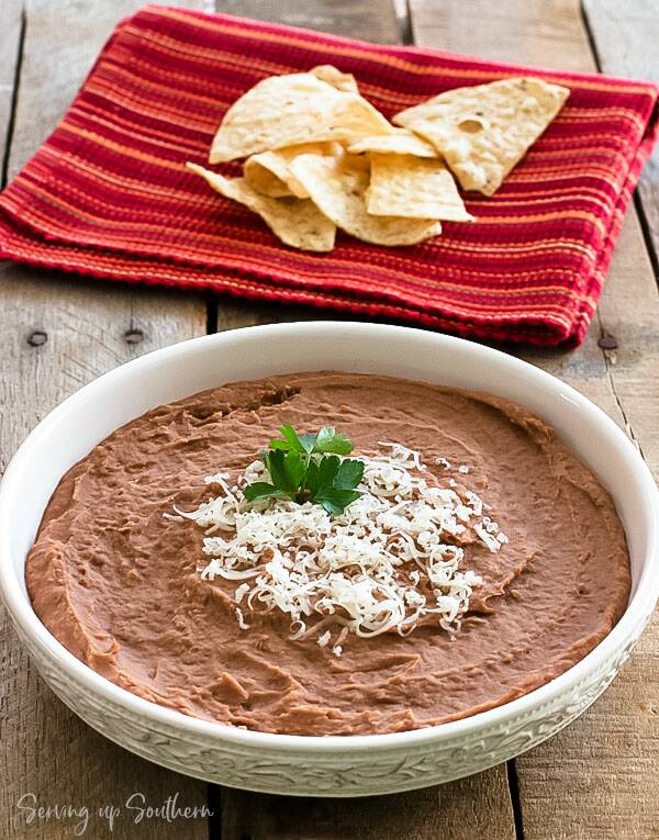 Bowl of refried beans sitting on a wooden board