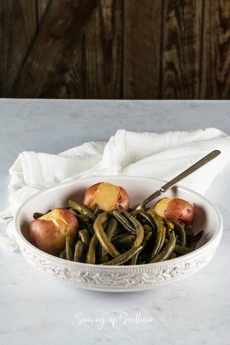 Southern style green beans in a white bowl on a marble surface