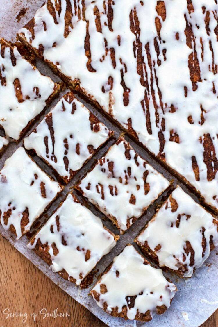 Snickerdoodle Blondies sitting on parchment paper on a wooden board.