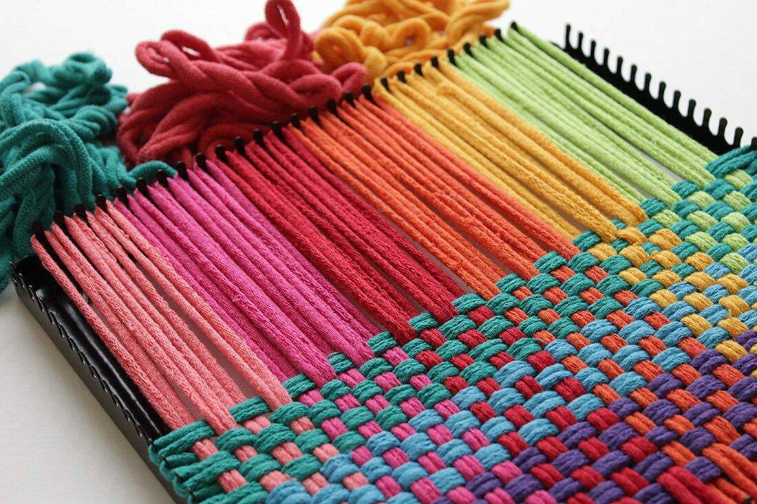 Picture of a potholder loom with a colorful potholder partially finished.