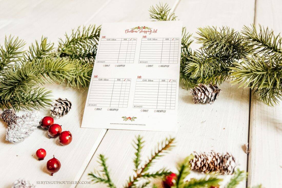 Printable shopping list on white wooden board with greenery and cranberries.