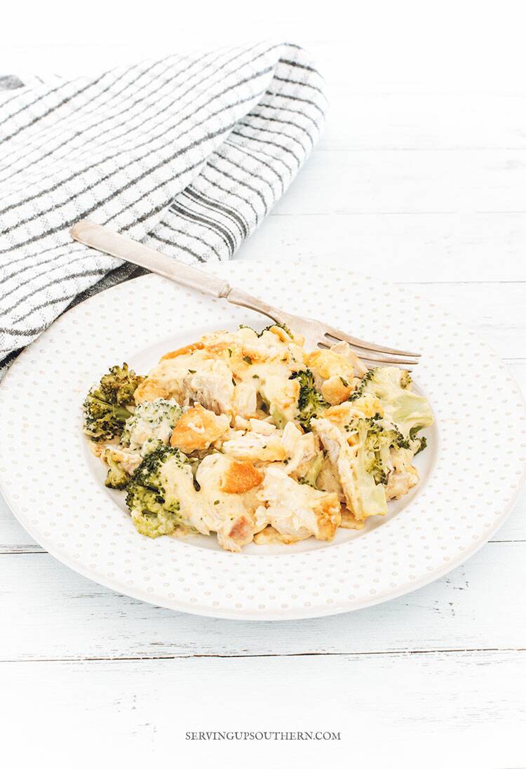 Chicken Divan plated on a white plate with a silver fork on a wooden surface.