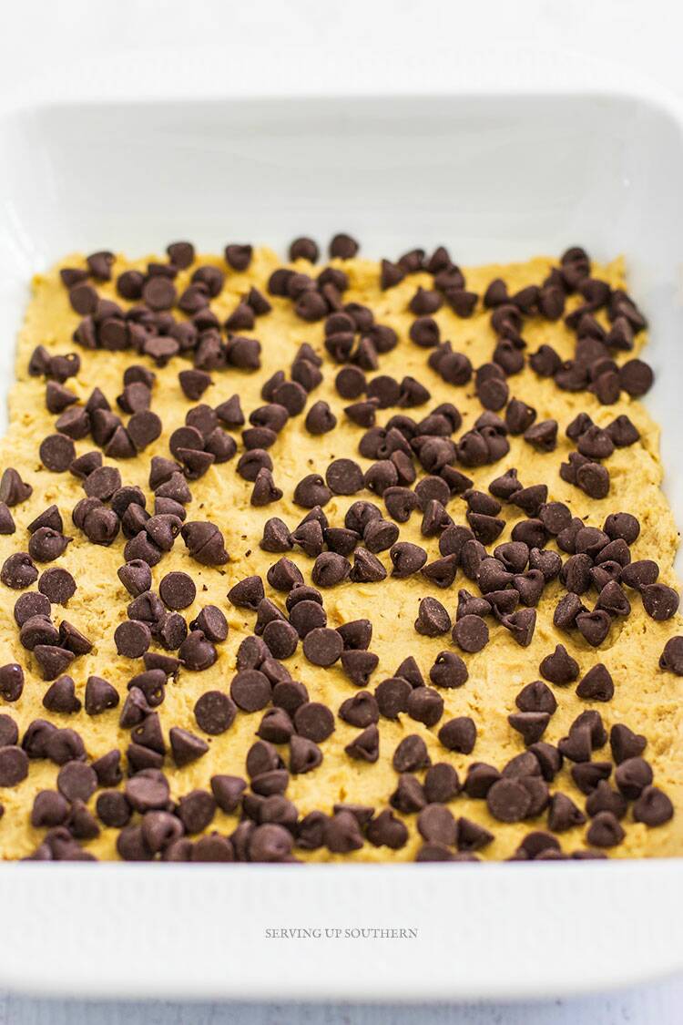 White baking dish filled with peanut butter chocolate chip bars ready to go into oven.