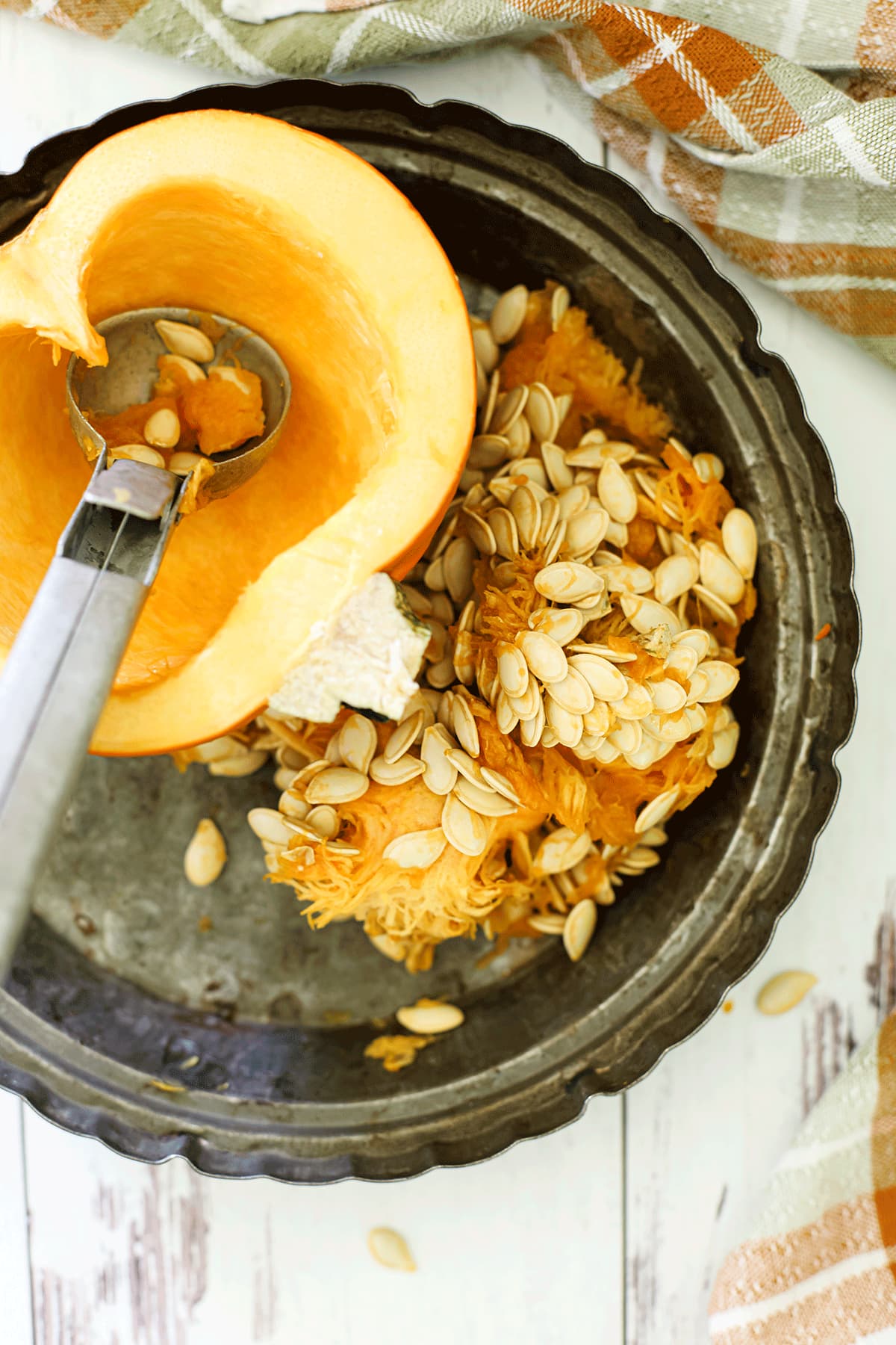 One half of a pumpkin being scooped out with an ice cream scoop.