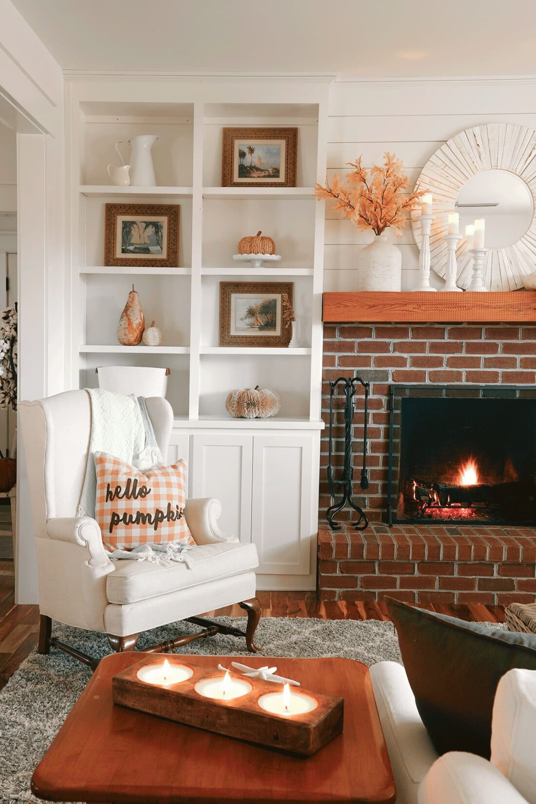 Close up picture of bookshelves, fireplace, and chair decorated for fall.
